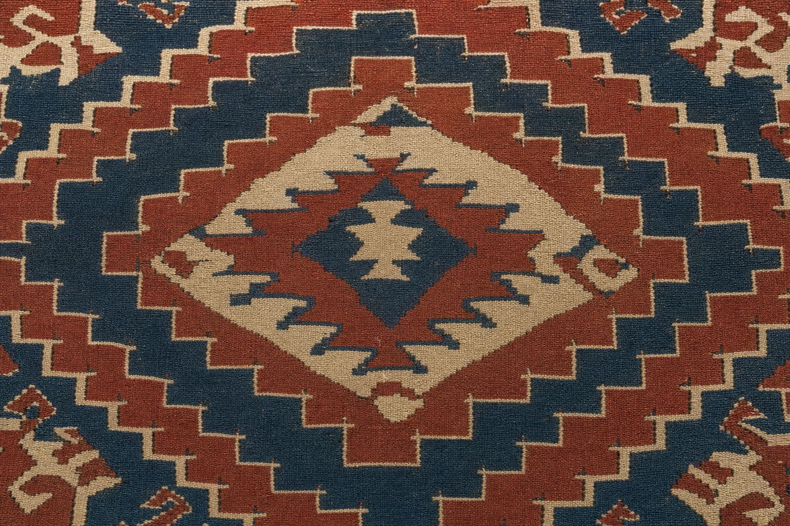 Detail of a flatwoven kilim with stepped diamond medallions in madder red, indigo and ivory