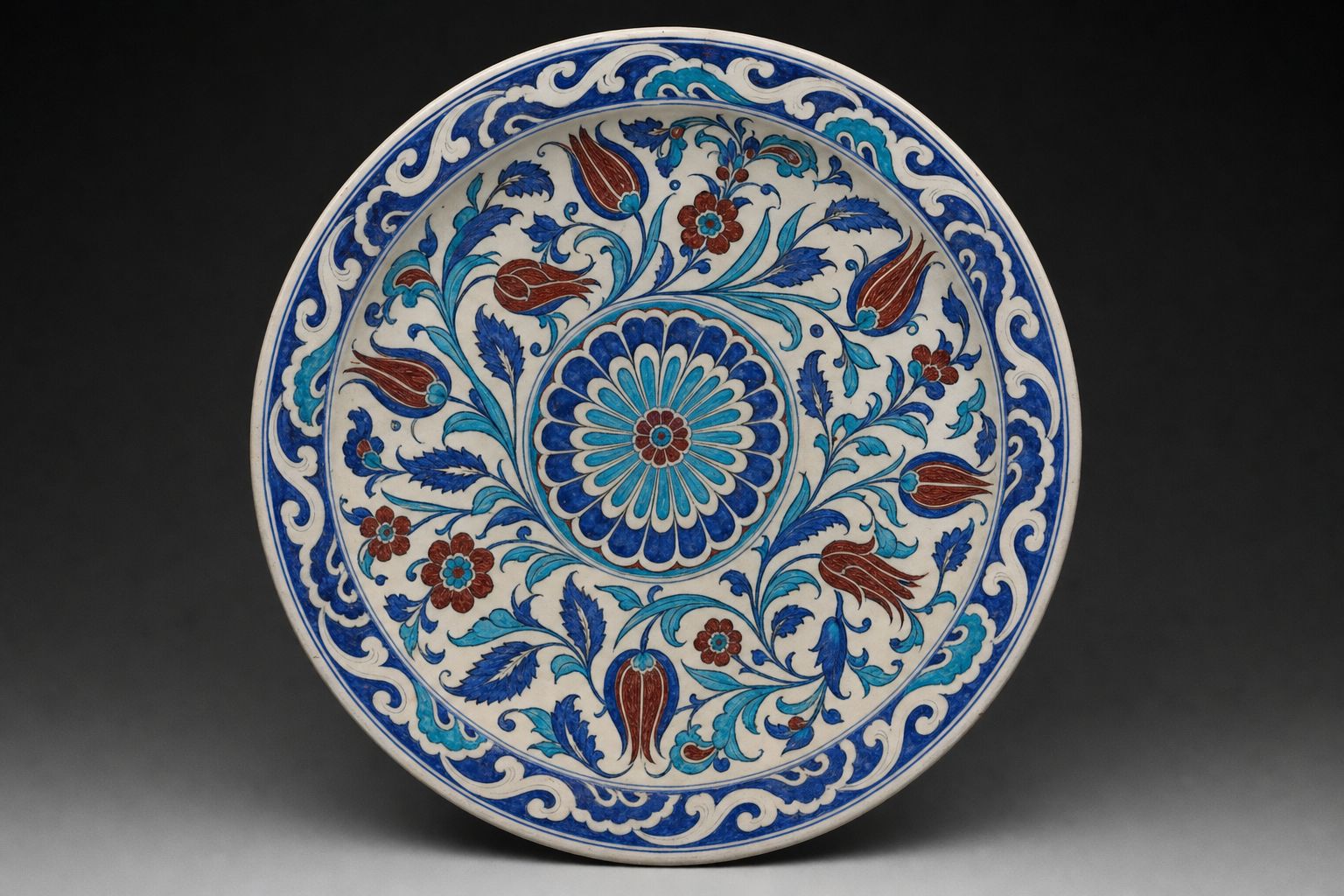 A large ceramic dish painted with a rosette, saz leaves and tulips in cobalt, turquoise and red