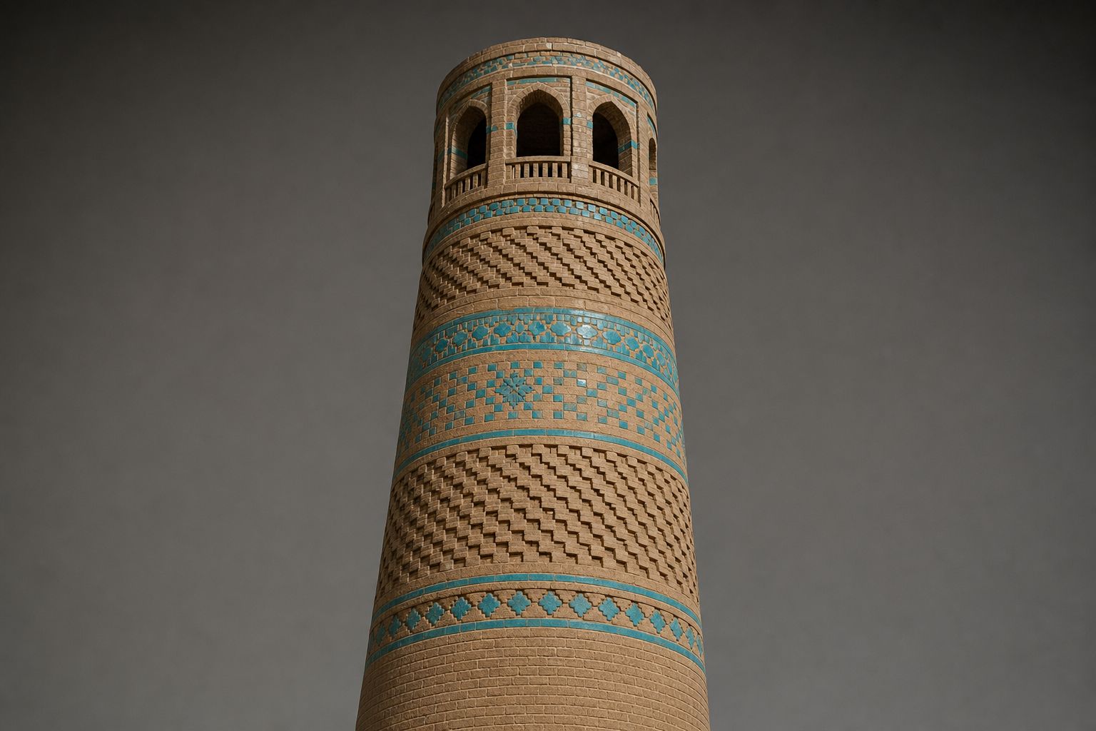 A tall brick minaret banded with patterned brickwork and inset turquoise glazed tiles